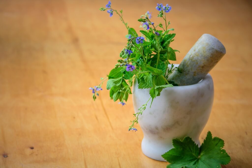 Balmy Herb Marble mortar and pestle with fresh herbs and flowers on wooden table enhancing natural health and cooking aesthetics.