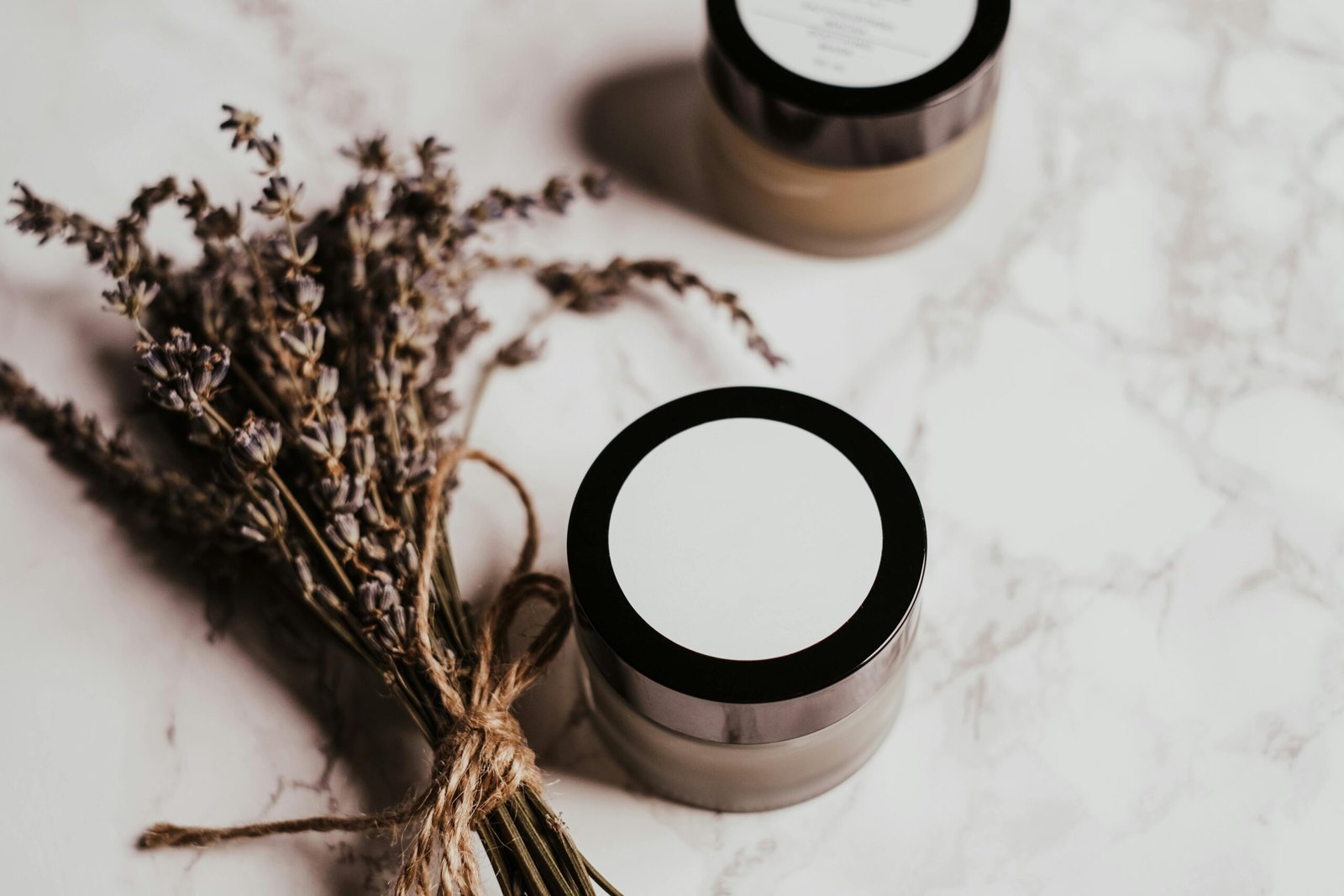 Aesthetic arrangement of skincare products and lavender on marble for beauty promotion.